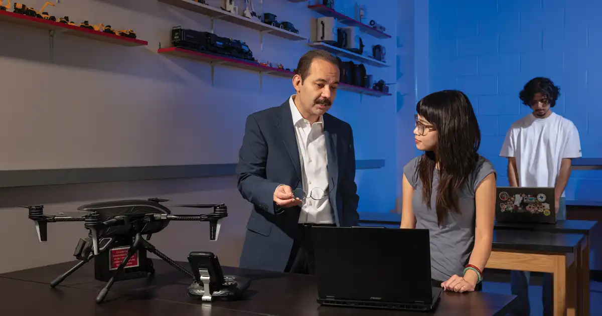 Mohsen Shahandashti speaks with an engineering student in a classroom setting.